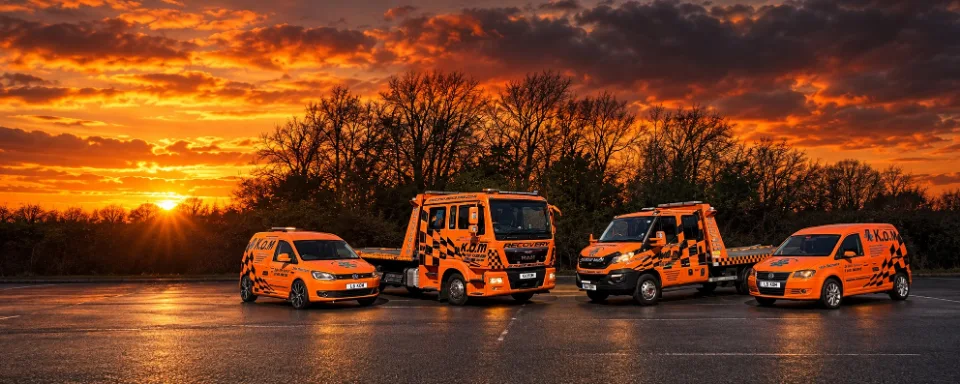 Illustration of four orange K.O.M recovery vehicles at sunset