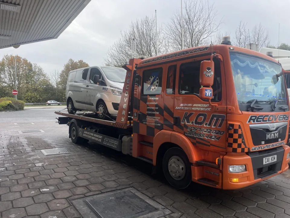 K.O.M flatbed recovery truck carrying a vehicle