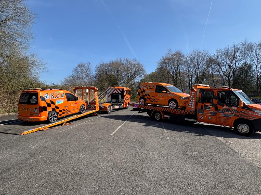 Orange K.O.M recovery trucks and vans with a loading ramp lowered